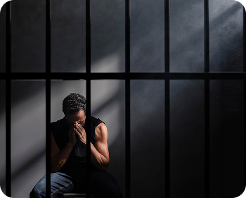 A moody, dark image of a person sitting alone, symbolizing reflection or incarceration.